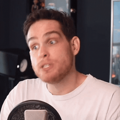 A Man With A Beard Is Sitting In Front Of A Microphone Making A Funny Face GIF