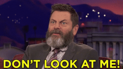 A Man With A Beard Is Sitting In Front Of A Sign That Says " Do N't Look At Me " GIF