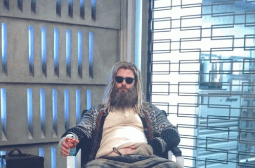 A Man With A Beard Is Sitting In Front Of A Window GIF
