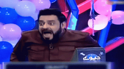 A Man With A Beard Is Sitting In Front Of Balloons And A Sign That Says " Jio " GIF