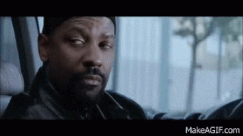 A Man With A Beard Is Sitting In The Back Seat Of A Car Looking Out The Window . GIF