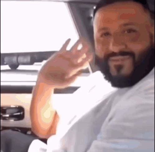 A Man With A Beard Is Sitting In The Driver 'S Seat Of A Car . GIF