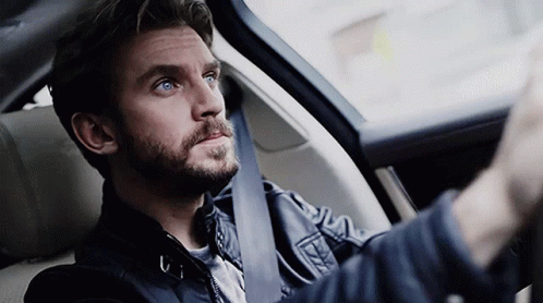 A Man With A Beard Is Sitting In The Driver 'S Seat Of A Car GIF