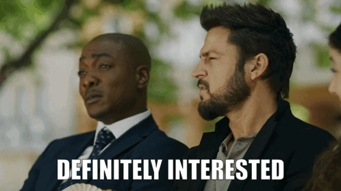 A Man With A Beard Is Sitting Next To Another Man With The Words Definitely Interested Above Him GIF