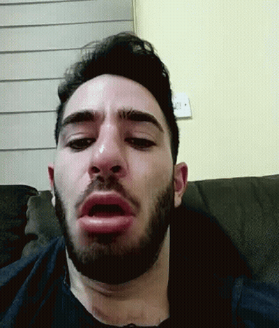 A Man With A Beard Is Sitting On A Couch And Making A Funny Face GIF