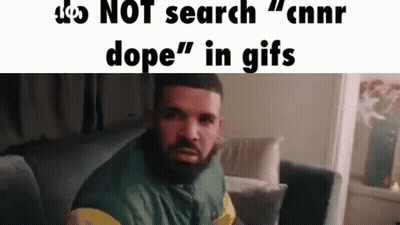 A Man With A Beard Is Sitting On A Couch In A Living Room And Looking At The Camera . GIF