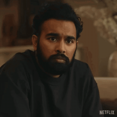 A Man With A Beard Is Sitting On A Couch With His Eyes Closed And A Black Shirt On . GIF