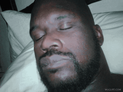 A Man With A Beard Is Sleeping On A Bed With Muglife.com Written On The Bottom Right GIF