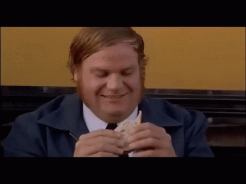 A Man With A Beard Is Smiling And Eating A Sandwich GIF