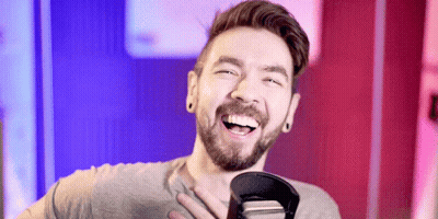 A Man With A Beard Is Smiling And Holding A Microphone GIF