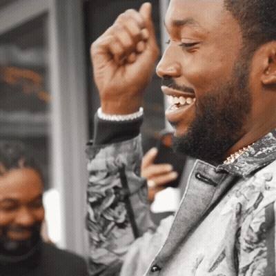 A Man With A Beard Is Smiling And Holding His Fist Up GIF