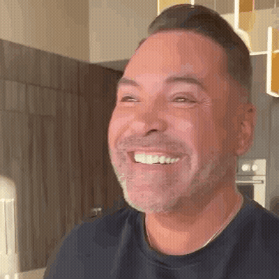 A Man With A Beard Is Smiling And Looking At The Camera . GIF