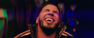 A Man With A Beard Is Smiling And Looking At The Camera GIF