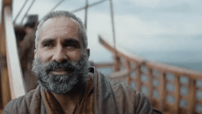A Man With A Beard Is Smiling And Looking To The Side GIF
