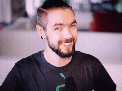 A Man With A Beard Is Smiling And Wearing A Black Shirt With A Snake On It GIF