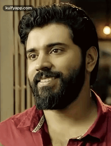 A Man With A Beard Is Smiling And Wearing A Red Shirt GIF