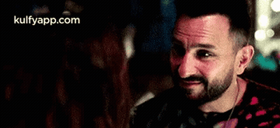 A Man With A Beard Is Smiling At A Woman In A Restaurant . GIF