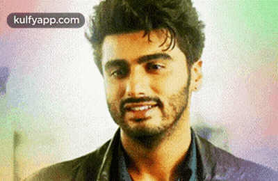 A Man With A Beard Is Smiling For The Camera . GIF