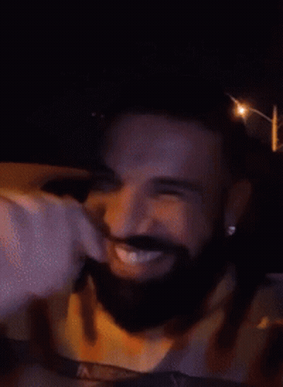 A Man With A Beard Is Smiling In A Car At Night GIF
