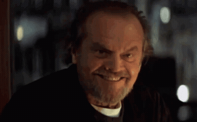 A Man With A Beard Is Smiling In A Dark Room . GIF