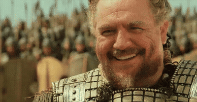 A Man With A Beard Is Smiling In Front Of A Crowd Of Soldiers . GIF