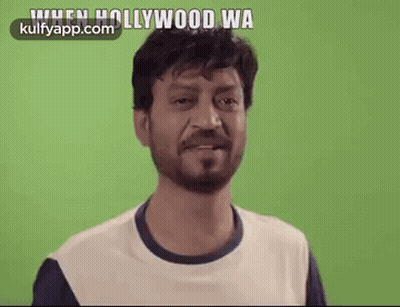 A Man With A Beard Is Smiling In Front Of A Green Screen And Says `` When Hollywood Wants To '' . GIF