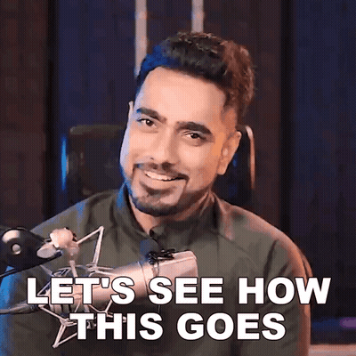A Man With A Beard Is Smiling In Front Of A Microphone And Says Let 'S See How This Goes GIF