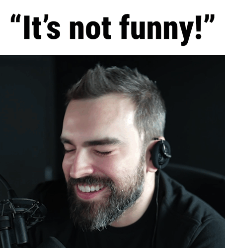 A Man With A Beard Is Smiling In Front Of A Microphone With The Words " It 'S Not Funny " Written Above Him GIF