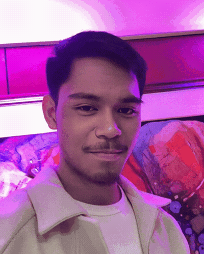 A Man With A Beard Is Smiling In Front Of A Painting GIF