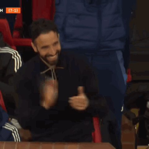 A Man With A Beard Is Smiling In Front Of A Scoreboard With The Number 7 On It GIF