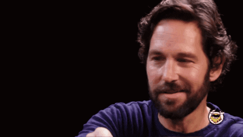 A Man With A Beard Is Smiling In Front Of A Sign That Says Look At Us GIF