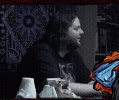 A Man With A Beard Is Smiling In Front Of A Wall Tapestry And The Words Dafug ? GIF