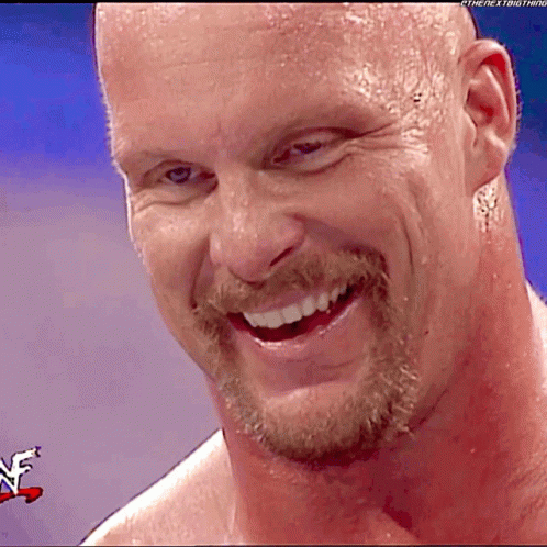 A Man With A Beard Is Smiling In Front Of A Wrestler Logo GIF