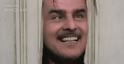 A Man With A Beard Is Smiling While Looking Through A Door . GIF