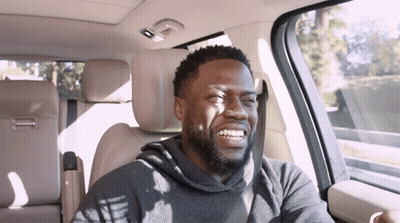 A Man With A Beard Is Smiling While Sitting In A Car GIF