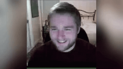 A Man With A Beard Is Smiling While Sitting In Front Of A Computer Monitor . GIF