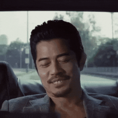 A Man With A Beard Is Smiling While Sitting In The Back Seat Of A Car GIF