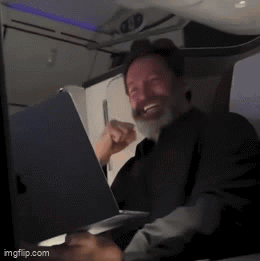 A Man With A Beard Is Smiling While Using A Laptop GIF