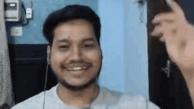 A Man With A Beard Is Smiling While Wearing Headphones And A White Shirt . GIF