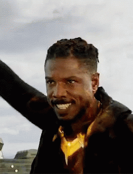 A Man With A Beard Is Smiling With His Arms Outstretched In The Air . GIF