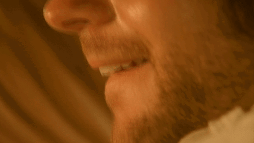 a man with a beard is smiling with his mouth open .