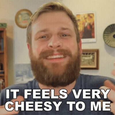 A Man With A Beard Is Smiling With The Words It Feels Very Cheesy To Me Below Him GIF