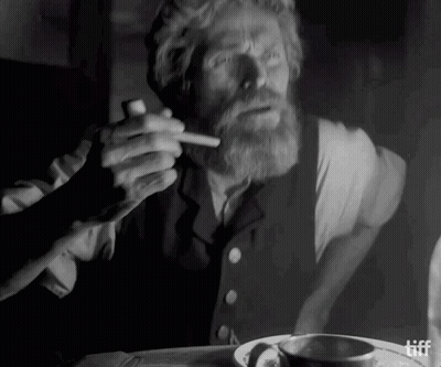 A Man With A Beard Is Smoking A Cigarette In A Black And White Photo .. GIF