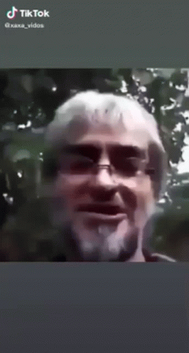 A Man With A Beard Is Smoking A Cigarette In A Tiktok Video . GIF