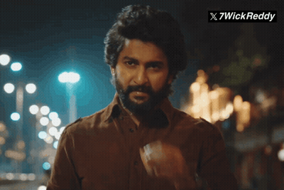 A Man With A Beard Is Smoking A Cigarette In Front Of A Sign That Says X7wick Reddy GIF