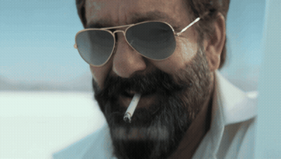 A Man With A Beard Is Smoking A Cigarette GIF
