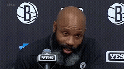 A Man With A Beard Is Speaking Into A Microphone . GIF