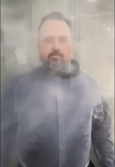 A Man With A Beard Is Standing Behind A Clear Glass GIF