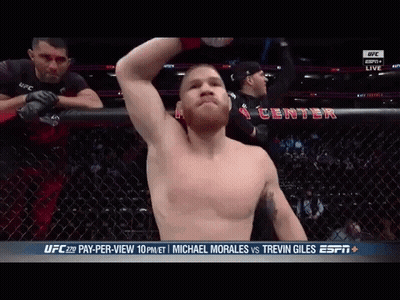 A Man With A Beard Is Standing In A Cage With A Sign That Says Ufc On It GIF
