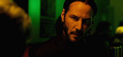 A Man With A Beard Is Standing In A Dark Room GIF